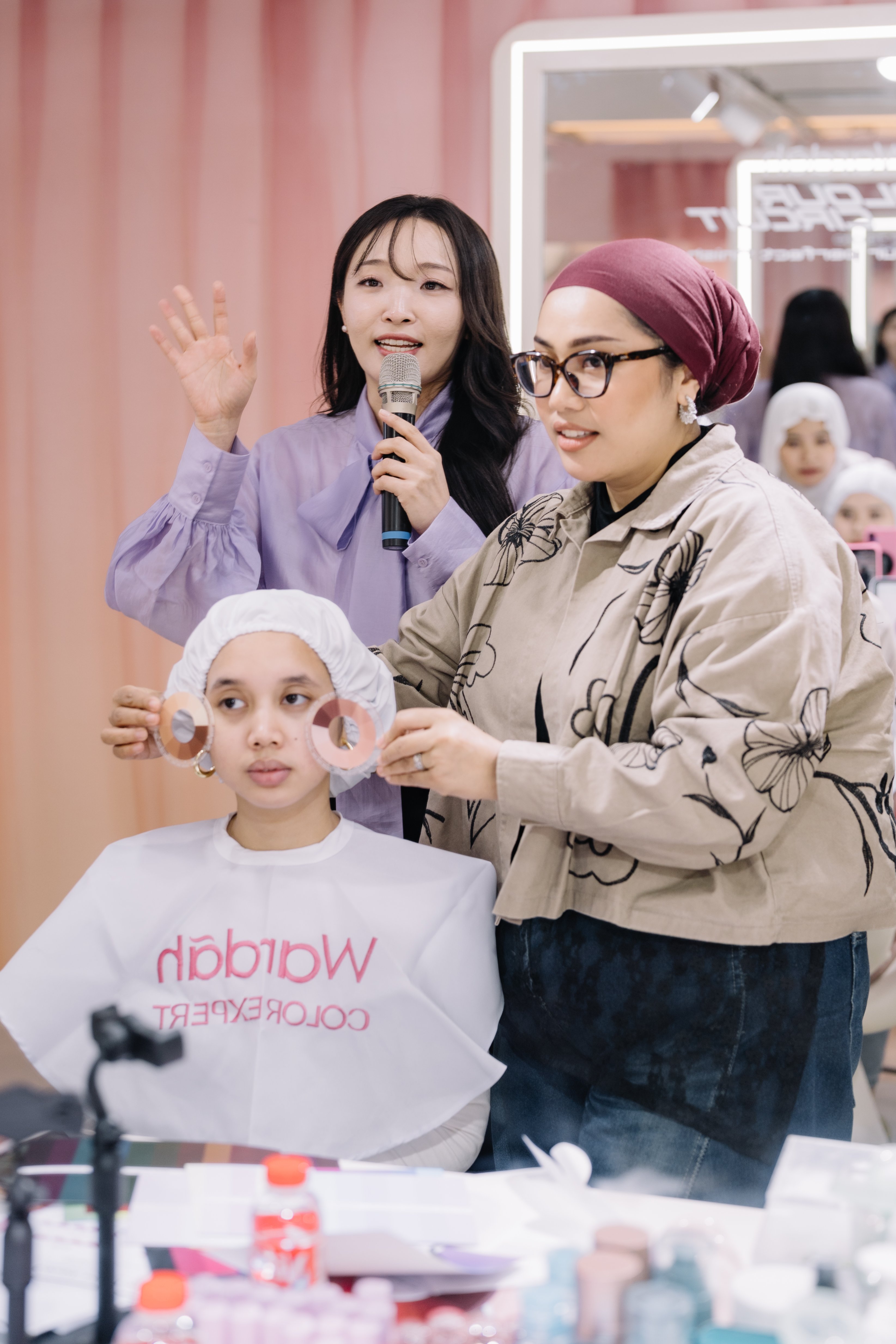 Color consultants holding a color swatch next to a guest at the Wardah collaboration event